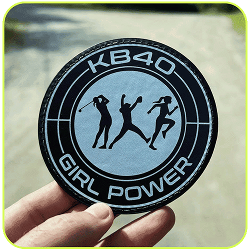 A round KB40 Girl Power patch held against a fence